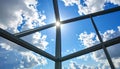 Sun shining through a modern glass ceiling grid with blue sky and white clouds skylight Royalty Free Stock Photo