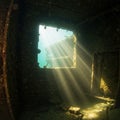 Sunlight streams into an underwater shipwreck through a square opening, illuminating Royalty Free Stock Photo