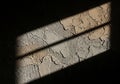 Sunlight streams through a window, casting shadows on a textured wall. The wall Royalty Free Stock Photo