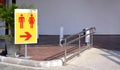 Restroom sign on metal pole with stainless steel fence on the different level ground in parking area Royalty Free Stock Photo