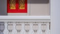 Sunlight on traditional pattern surface of white fence with red and golden wooden window on white concrete wall of Thai temple Royalty Free Stock Photo