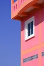 Sunlight on white glass window surface of vintage colorful pink building against blue clear sky Royalty Free Stock Photo