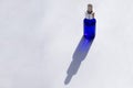 Sunlit blue galss bottle with pipette full of skin care serum on white background with long shadows.