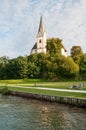 Sunlit church in the village of Maria Worth on the shores of Lake Worthersee in the Austrian mountains. High church clock tower, p Royalty Free Stock Photo