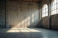 Sunlit industrial interior with aged concrete wall, windows. Sunbeams through window panes create shadows on floor. Architecture Royalty Free Stock Photo