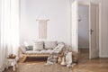 Sunlit living room interior with open door, herringbone parquet floor, natural, beige textiles and white walls Royalty Free Stock Photo