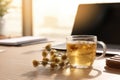 Sunlit Office Desk with Herbal Tea and Flowers in a Calm Workspace. Royalty Free Stock Photo