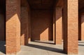 Sunlit red brick pillars create dramatic shadow play on sunlit ground. Architectural detail showcases geometric pattern of a Royalty Free Stock Photo