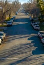 Sunlit road lined with vehicles and trees in Provo