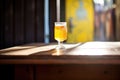 sunlit saison beer glass casting a shadow on a wooden table