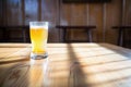 sunlit saison beer glass casting a shadow on a wooden table