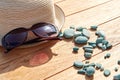 Sunlit straw hat, sunglasses and sea pebbles on the wooden table