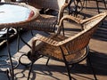 Sunlit wicker chairs sit at the table on a wooden veranda. Street Cafe Royalty Free Stock Photo