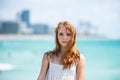 Sunner portrait of redhead beautiful girl at beach. Young tanned woman enjoying breeze at seaside. Carefree woman