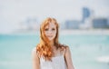 Sunner portrait of redhead beautiful girl at beach. Young tanned woman enjoying breeze at seaside. Carefree woman