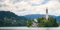 Sunning panoramic view of The island of Bled, Bled castle on cliff, Julian Alps and Church of the Assumption,Bled, Slovenia. Royalty Free Stock Photo