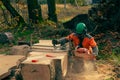 A man in an orange jacket cuts boards with an alaskan portable chainsaw mill. Royalty Free Stock Photo