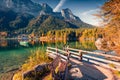 Sunny autumn view of Hintersee lake with wooden pier and fishing boat. Royalty Free Stock Photo