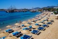 Sunny beach in Bodrum with umbrellas bathing people in clear turquoise water. Turkish paradise