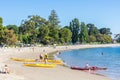 Sunny beach with swimmers and sea kayakers about to go for a paddle