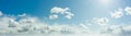 Sunny blue sky with fluffy clouds. Sunlight with rays illuminates the sky. Beautiful ultra-wide panoramic background of atmosphere