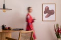 Sunny and bright space of living room with mock up poster frame, woman in red kimono, bouquet flower in vase and personal Royalty Free Stock Photo