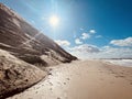 Sunny day on the beach between rocky coast and sea