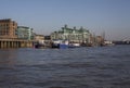 Sunny day, blue skies and shiny waters of the river Thames; buildings on the bank.