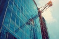 Sunny day construction site with modern office building and crane constructing a mirrored facade Royalty Free Stock Photo
