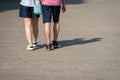 On a sunny day, a couple of people walk along the sidewalk. Royalty Free Stock Photo