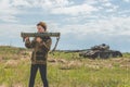 Girl in uniform with a Bazooka on the background of a broken tan