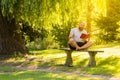 Sunny day - handsome bearded man sitting on a bench in lotus pose - padmasana in a park Royalty Free Stock Photo