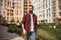 Sunny day. Handsome young bearded man in casual wear walking through the city street and smiling Royalty Free Stock Photo