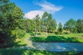 Sunny day, lake and meadow with blue sky. Treeas and clouds.