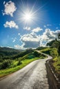 Sunny Day Over a Curved Country Road in a Lush Green Landscape Royalty Free Stock Photo