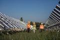 In a sunny day at photovoltaic solar farm walking in front of the camera group of investors and ecological engineer they