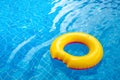 Sunny day at the pool.Bright yellow float in blue swimming pool, ring floating in a refreshing blue swimming pool with waves