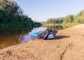 Sunny day on the river, stand up board on the river bank, tree reflections in the water, blue sky reflected in the river water Royalty Free Stock Photo