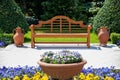 Sunny day in a spring garden with wooden bench, clay pots and blossoming flowers Royalty Free Stock Photo