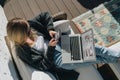 Sunny day. View from above. Young businesswoman is sitting on white couch, using laptop and smartphone with graphs