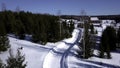 Sunny day in winter forest. Clip. Aerial view of a long road on snow covered ground among green trees. Royalty Free Stock Photo