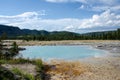 Sunny day in Yellowstone National Park, looking at a teal blue geyser hot spring Royalty Free Stock Photo