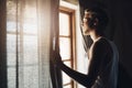 Sunny days always put a smile on my face. a handsome young man looking out of a window in his home. Royalty Free Stock Photo