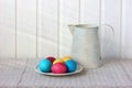 Sunny Easter still life with colorful eggs and a jug.