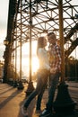 Sunny emotional shot of the loving couple smiling and holding hands in the sunset near the iron archway. Royalty Free Stock Photo