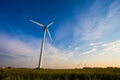 Sunny evening in countryside. Wind turbine in blue sky background. Renewable energy concept Royalty Free Stock Photo