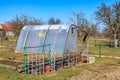 Sunny greenhouse in rural garden setting with bare trees and blue sky Royalty Free Stock Photo
