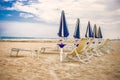 Sunny italy sand beach. Adriatic sea riviera. Blue and yellow deck chairs.