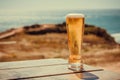 Sunny landscape with beer glass at outdoor bar. Ocean view with fresh drinks on natural background. Vacation concept