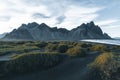 Sunny landscape of Iceland. Gorgeous view on Stokksnes cape and Vestrahorn Mountain with black sand with grass on